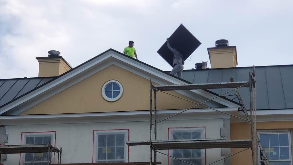 carefully carrying solar panels to the roof